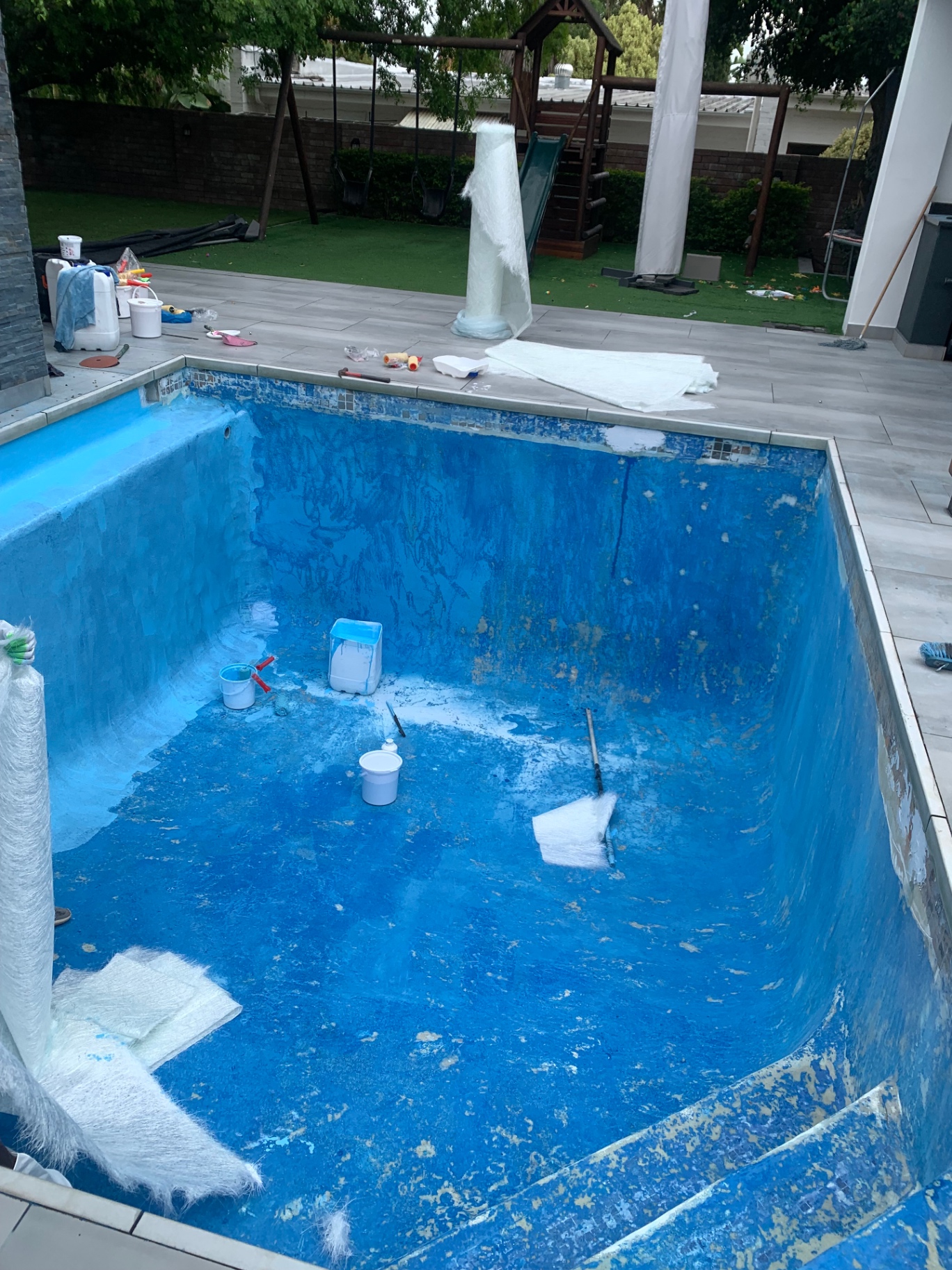 Fibreglass matting and resin being laid inside a pool shell during relining